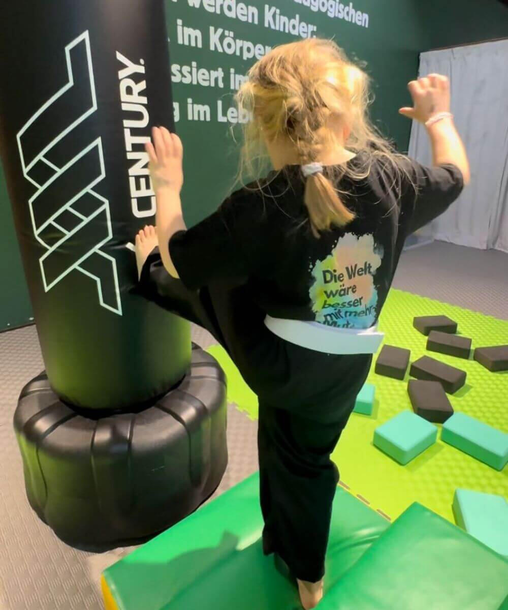 Kind tritt selbstbewusst gegen Boxsack in der ReFit Kids Halle